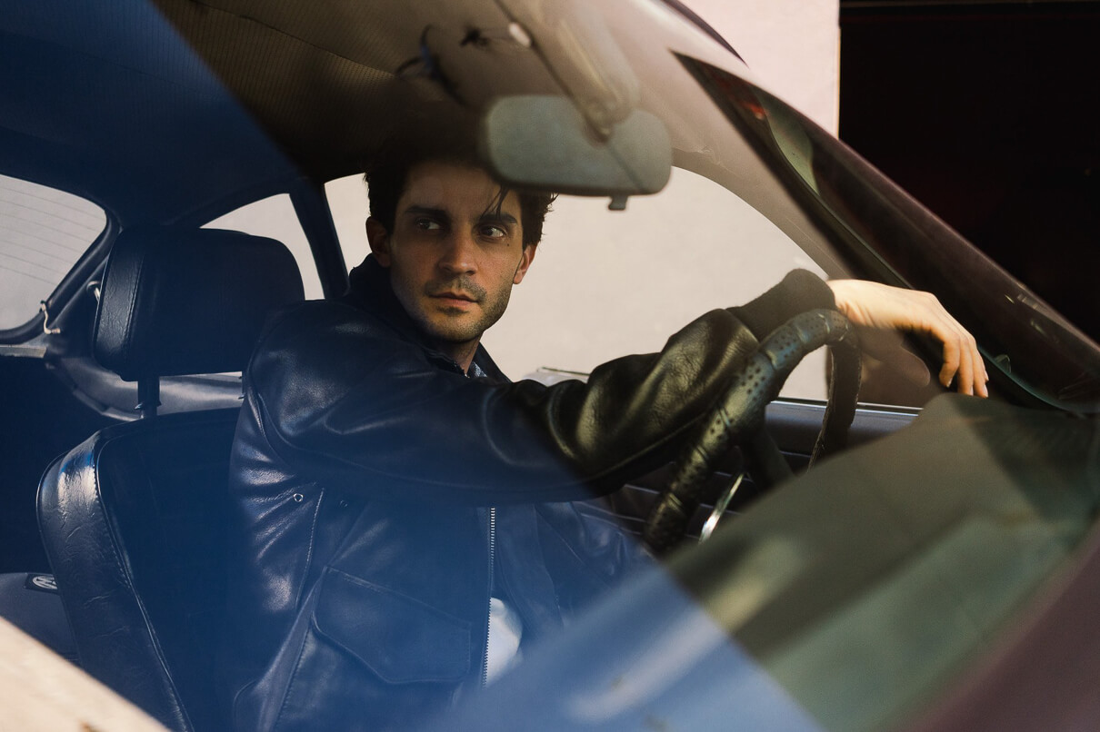 Man behind the wheel of a car wearing the 3sixteen/Schott collaboration A-2 jacket