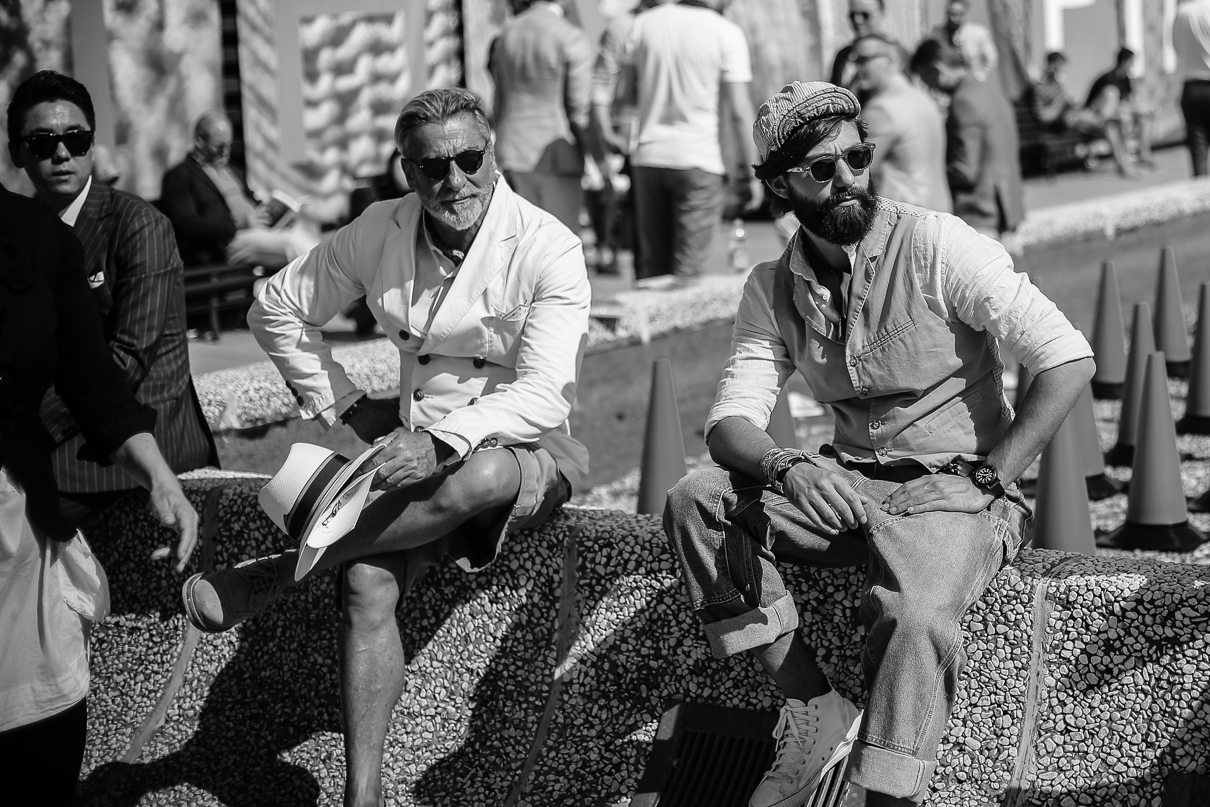 Well dressed men at the Pitti Uomo sitting on a wall
