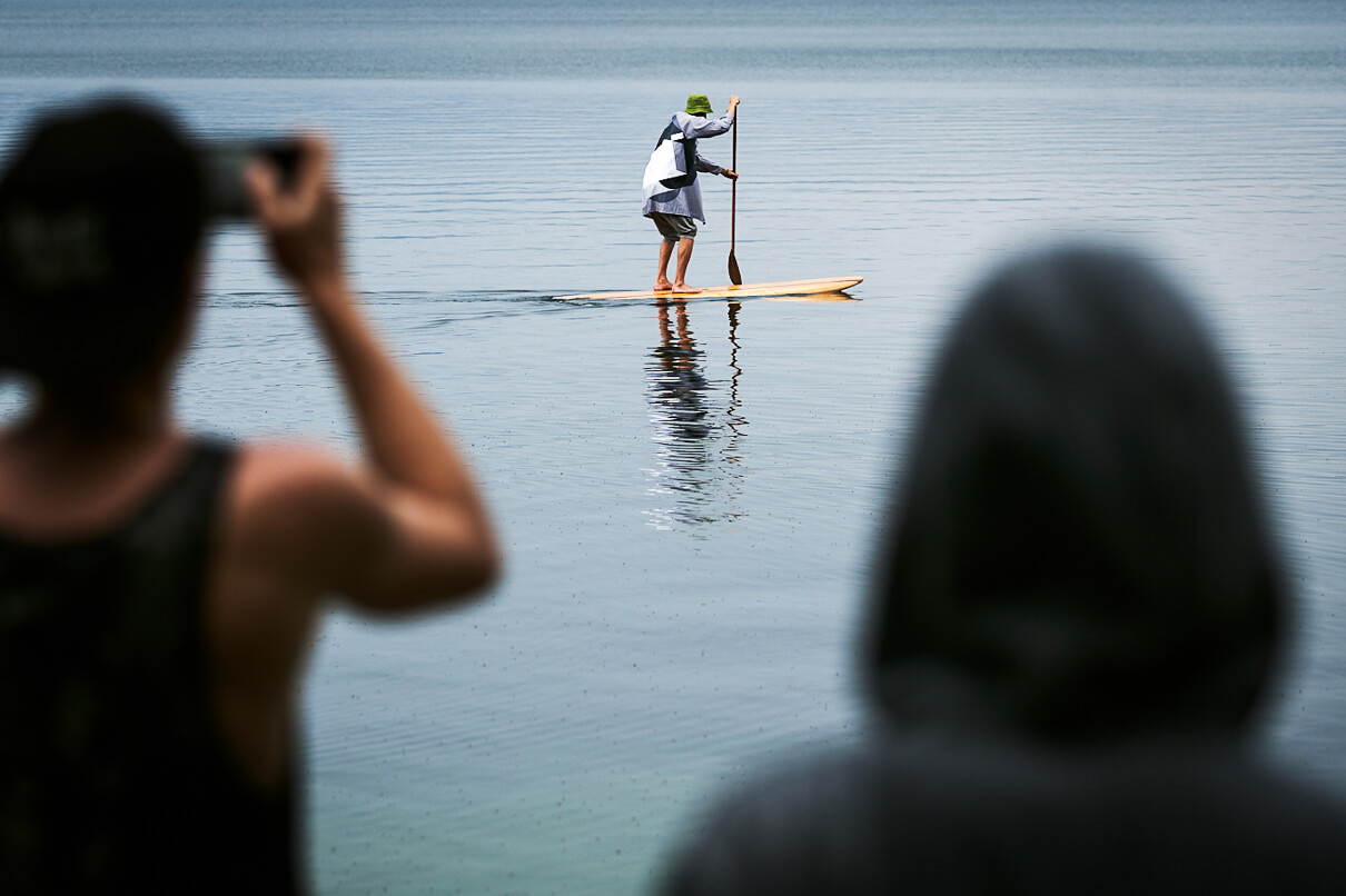 A Mitrich paddleboard in use on the water in front of an audaince.